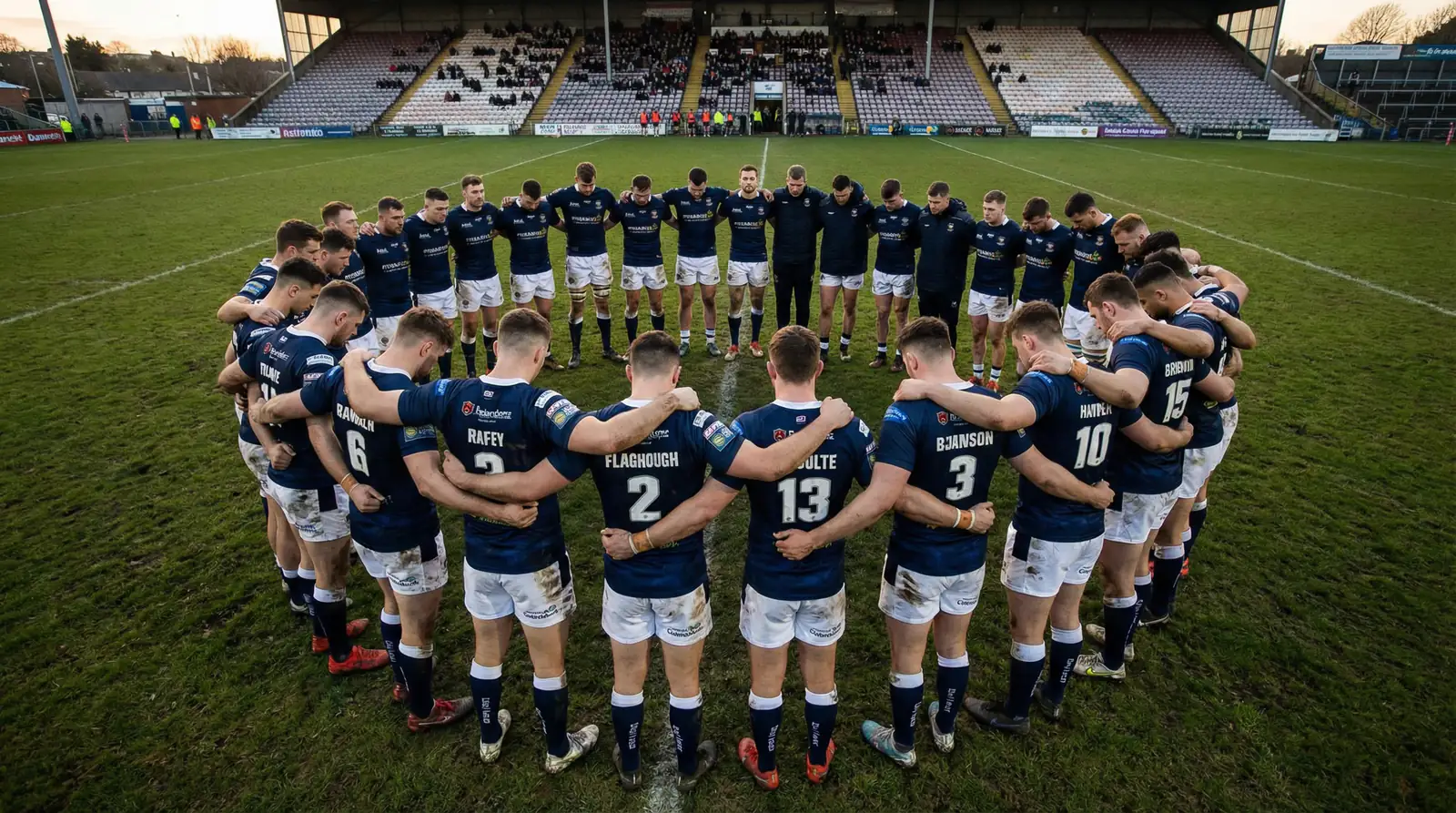 Rugby league team in a huddle on the field discussing strategy before a match