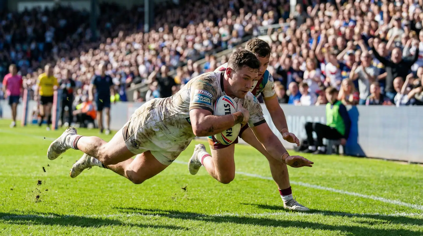 Rugby league players scoring a try on a sunlit grass pitch