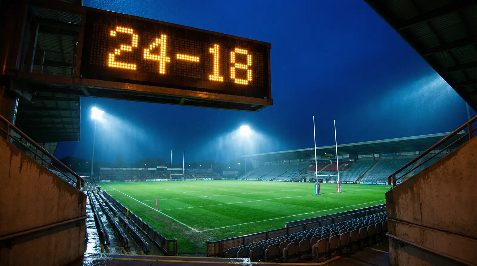Electronic scoreboard showing match points at a floodlit rugby league stadium at night
